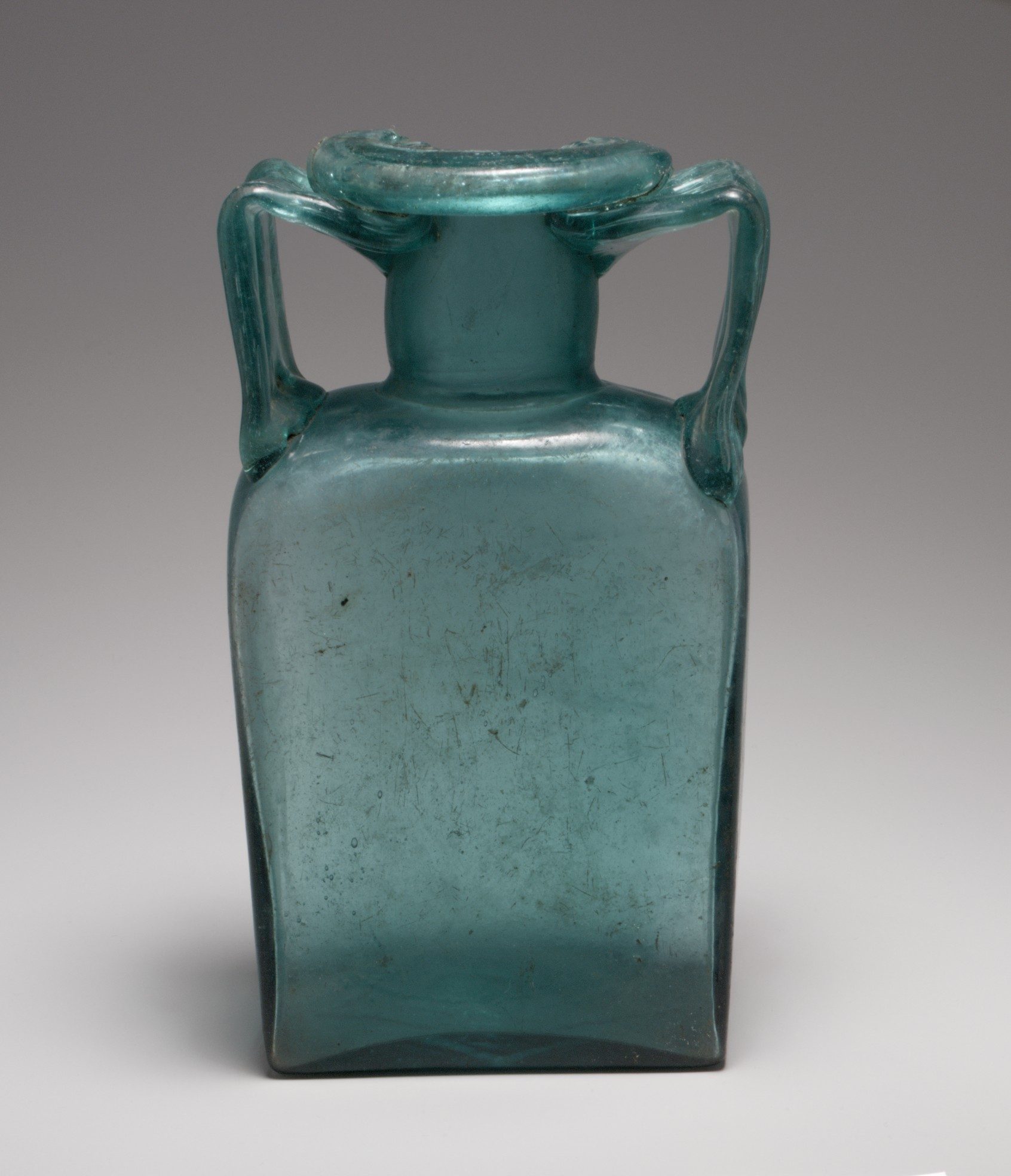 Roman mould-blown rectangular glass storage bottle, second to third century CE.
